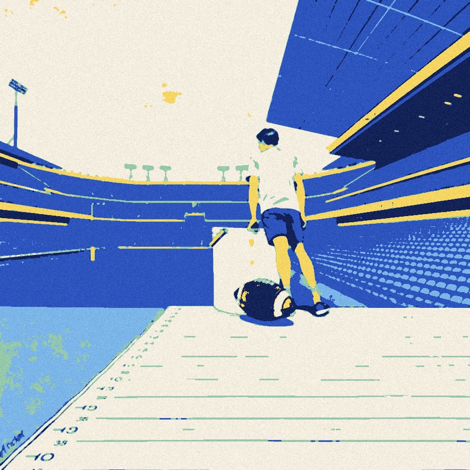 A tiny fan in a white shirt places a giant bucket on the bottom line of a huge grid in an empty stadium at dusk.