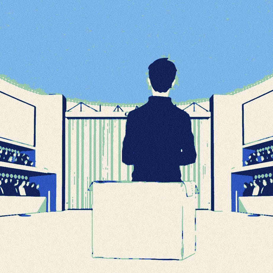 A tiny figure in dark clothing stands with folded arms beside a giant empty cardboard box in front of a stadium gate at night.