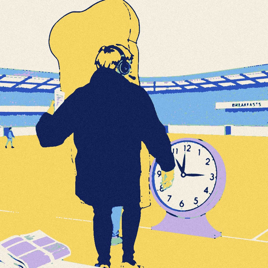 A tiny manager seen from behind stands beside a giant slice of toast and an oversized clock on a stadium touchline.