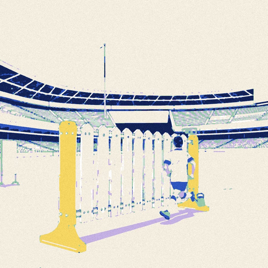 A tiny footballer seen from behind runs towards a giant garden hurdle placed outside a stadium.