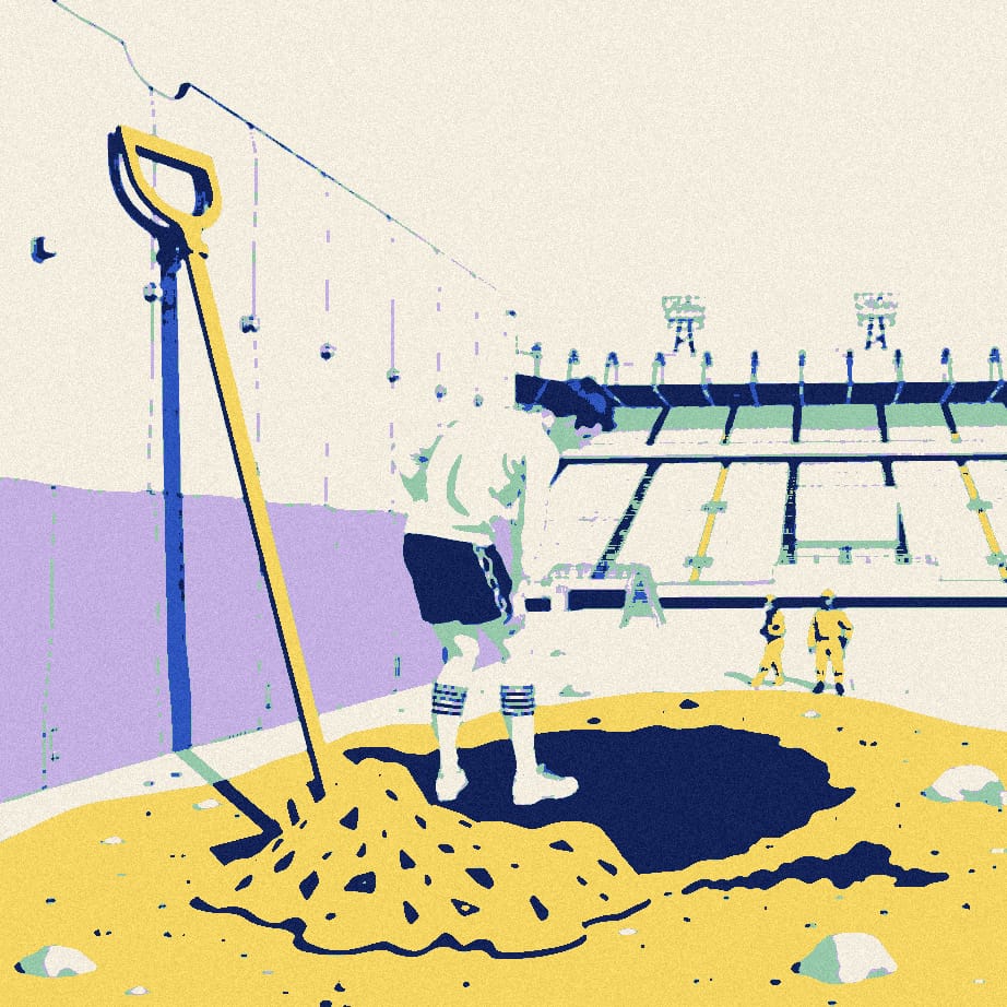 A small footballer in a white shirt, seen from behind, digs a hole beside a huge stadium wall with an oversized spade in the drizzle.