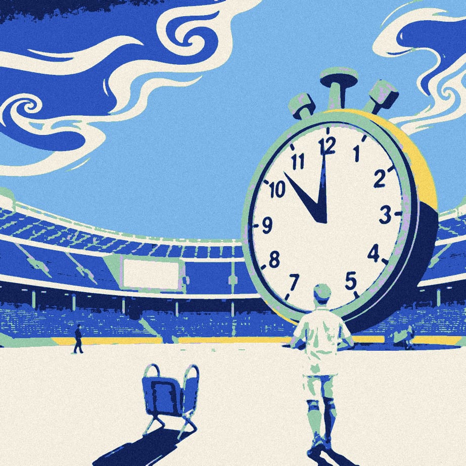 A tiny fan in a plain white shirt walks away from an enormous stopwatch in an empty stadium forecourt at dusk.