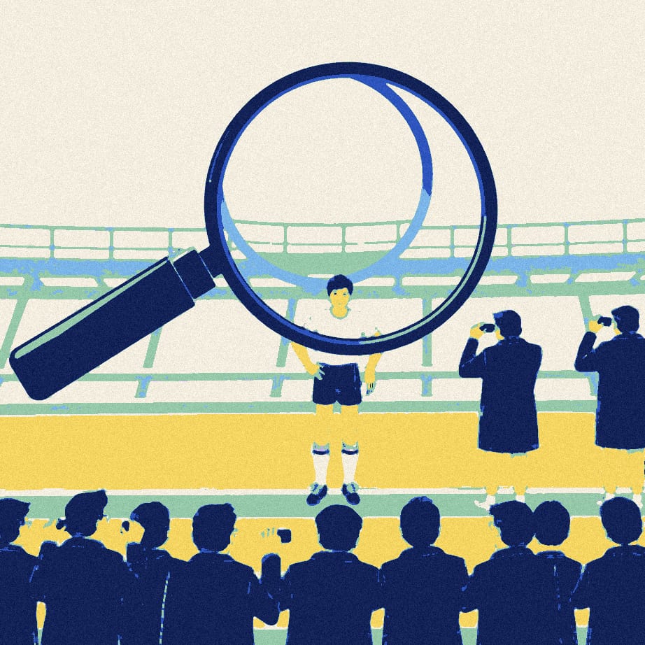 Eight anonymous figures in padded jackets crowd around a giant magnifying glass inspecting one tiny young footballer on an empty touchline.